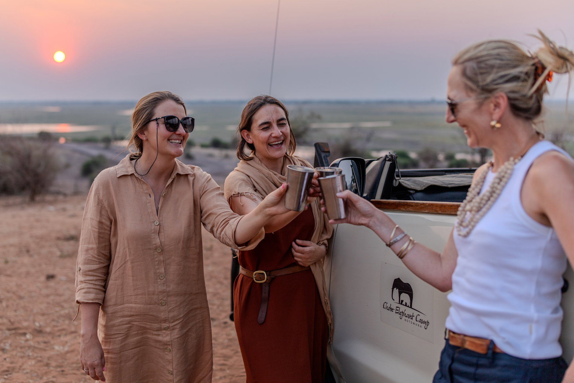 Guests raising a sundowner toast at sunset on the Chobe