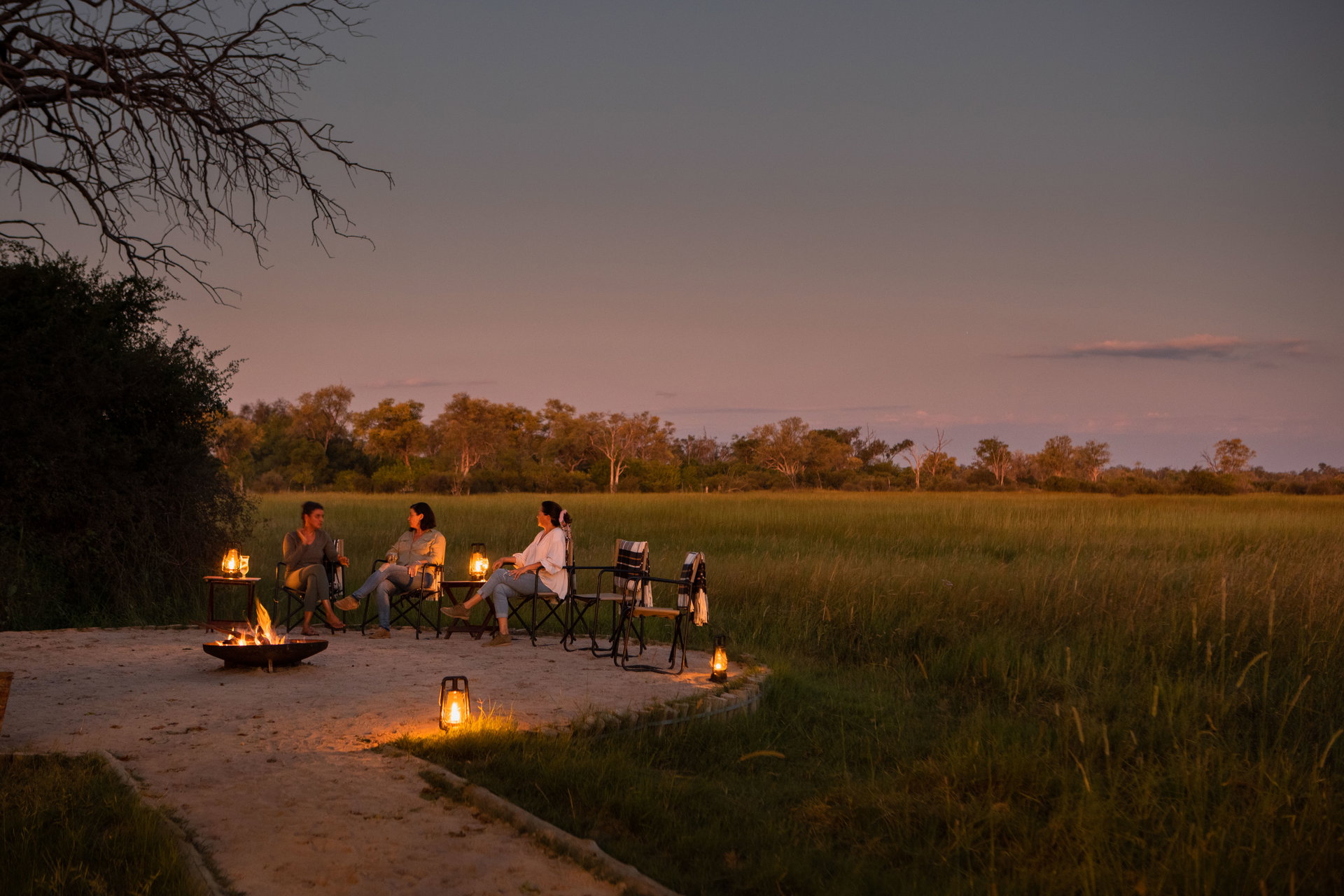 Guests around the fire pit at Little Sable at dusk, looking over the grassland