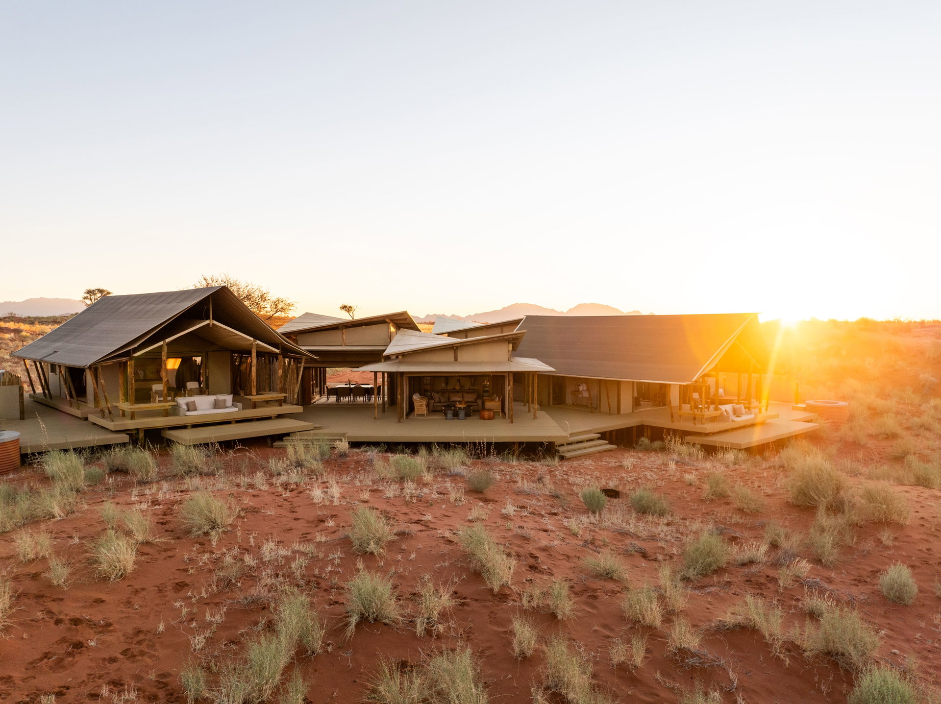 The tents of Wolwedans Dune Camp on the red sand at sunrise