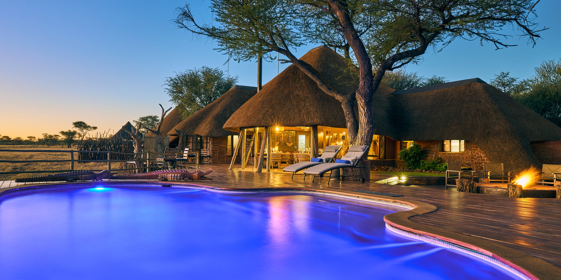 The pool and thatched main house of Okonjima African Villa at dusk