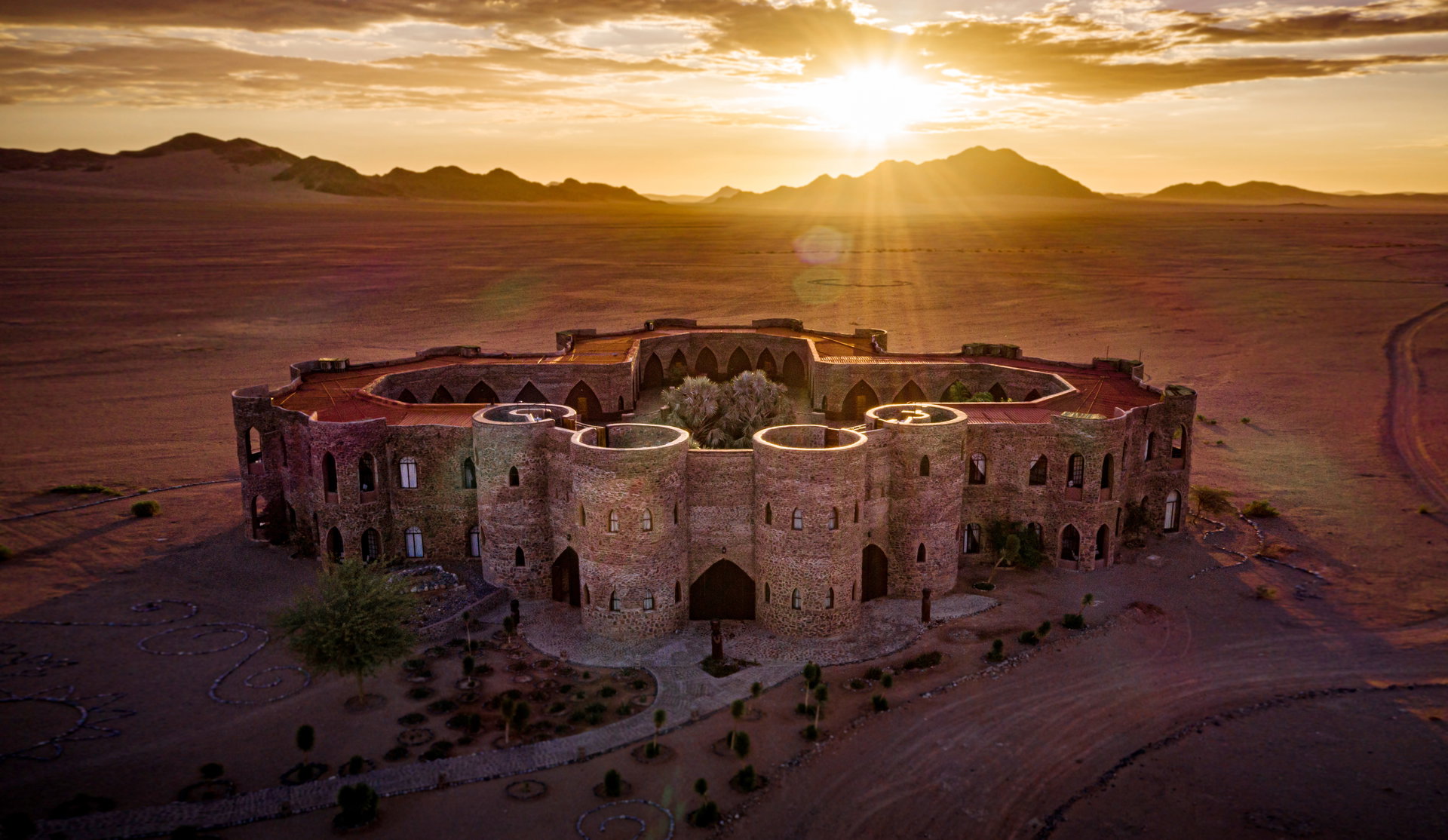 The stone castle-like buildings of Le Mirage at sunset on the plains near Sossusvlei