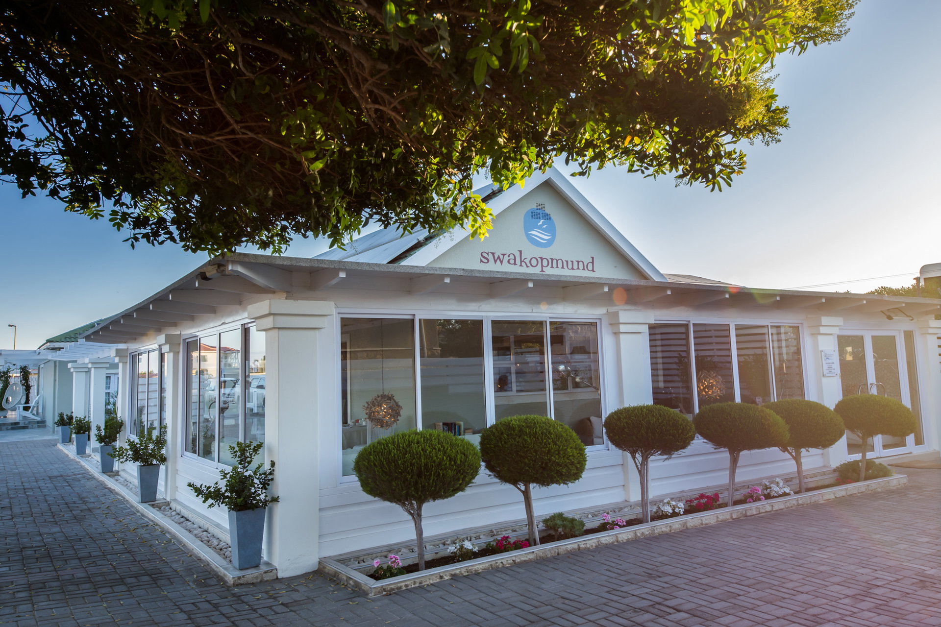The white front of Swakopmund Guesthouse with its clipped trees