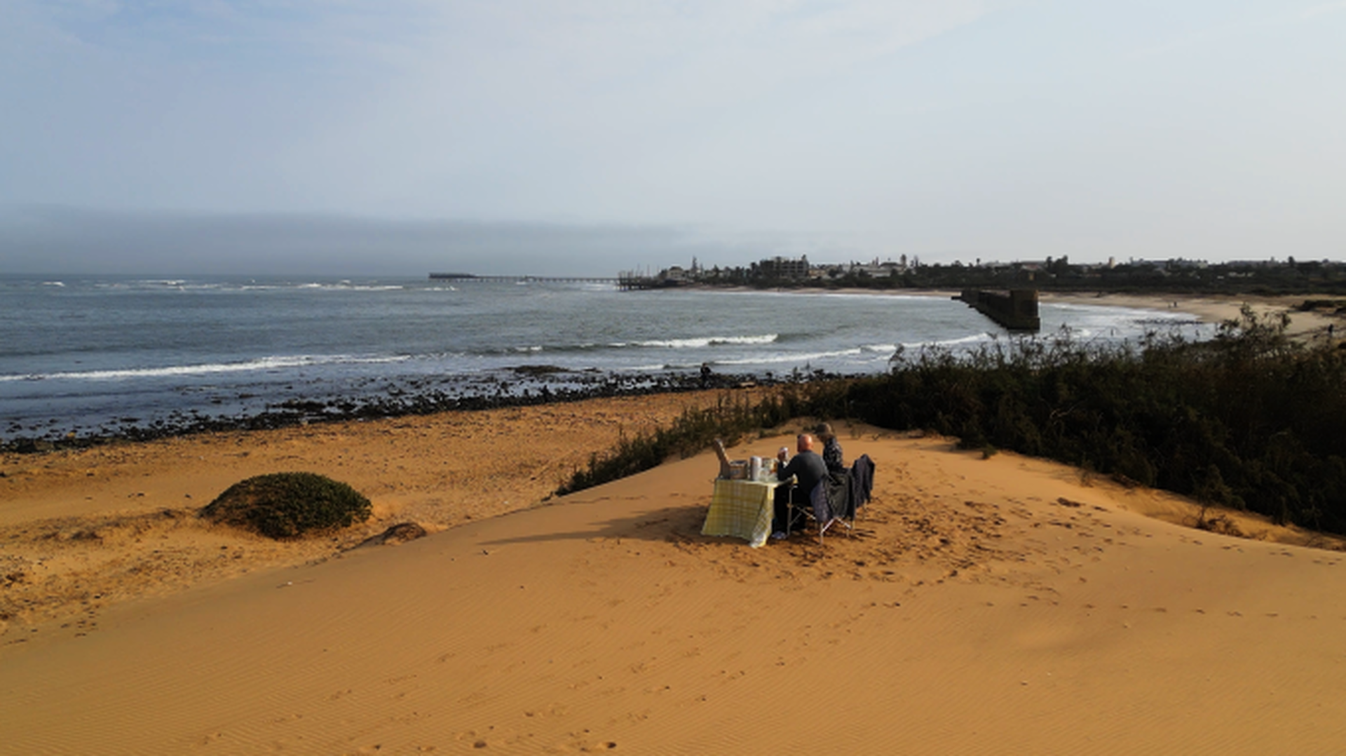 A breakfast table set on a small dune above the Atlantic beach