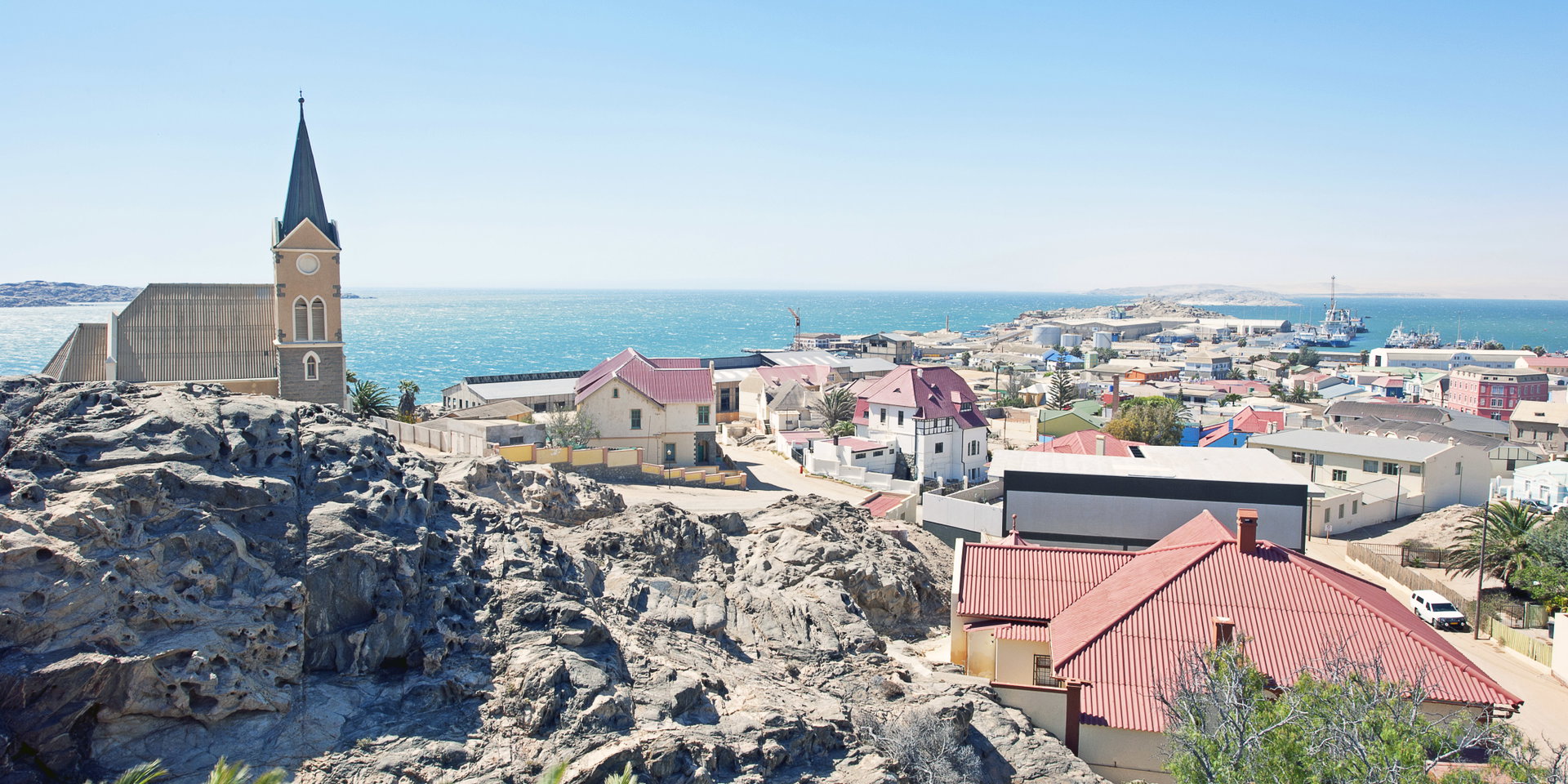 A hilltop church above the colourful rooftops of Lüderitz and the blue sea beyond.