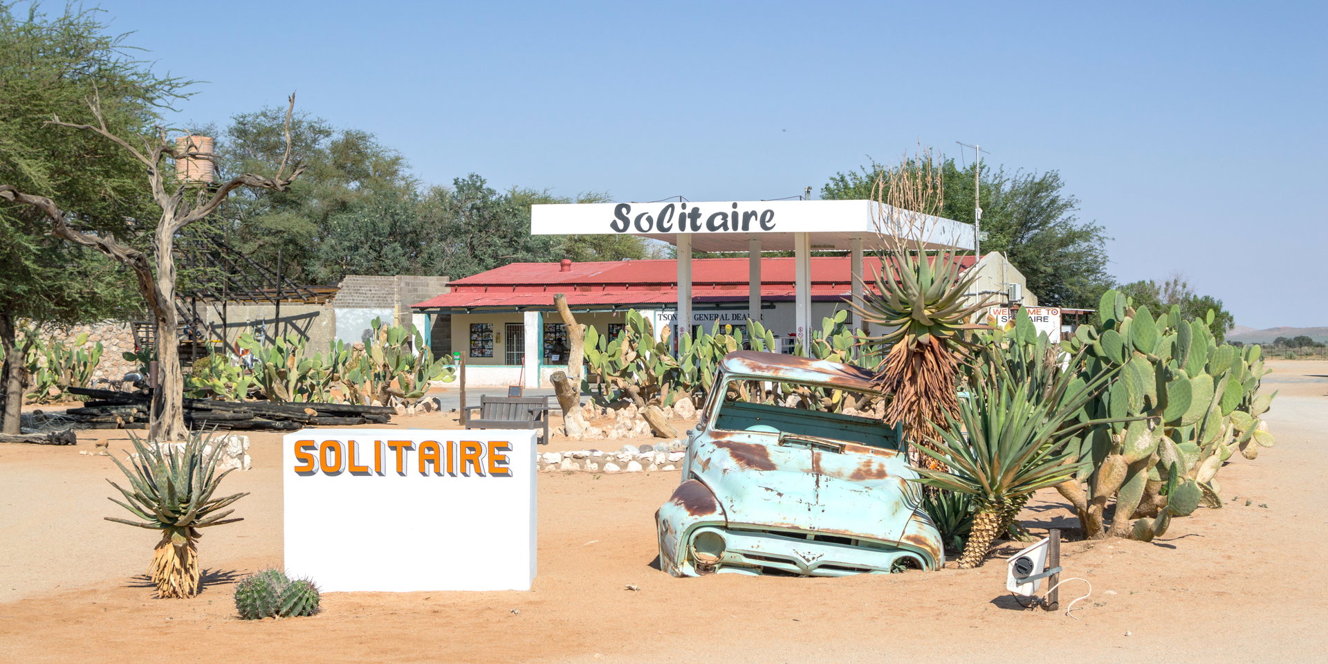 The Solitaire sign among cacti beside the fuel station and an old car