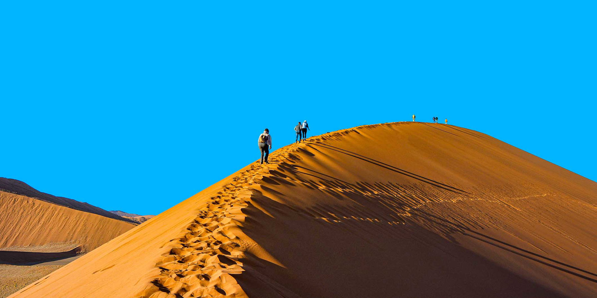 Hikers on the crest of a red dune at Sossusvlei