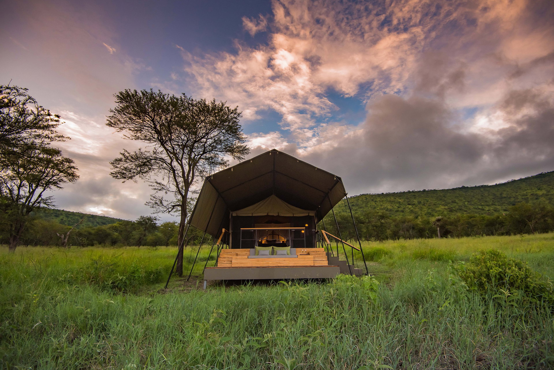 A tent with its deck in the green grass of the Serengeti at Dunia Camp