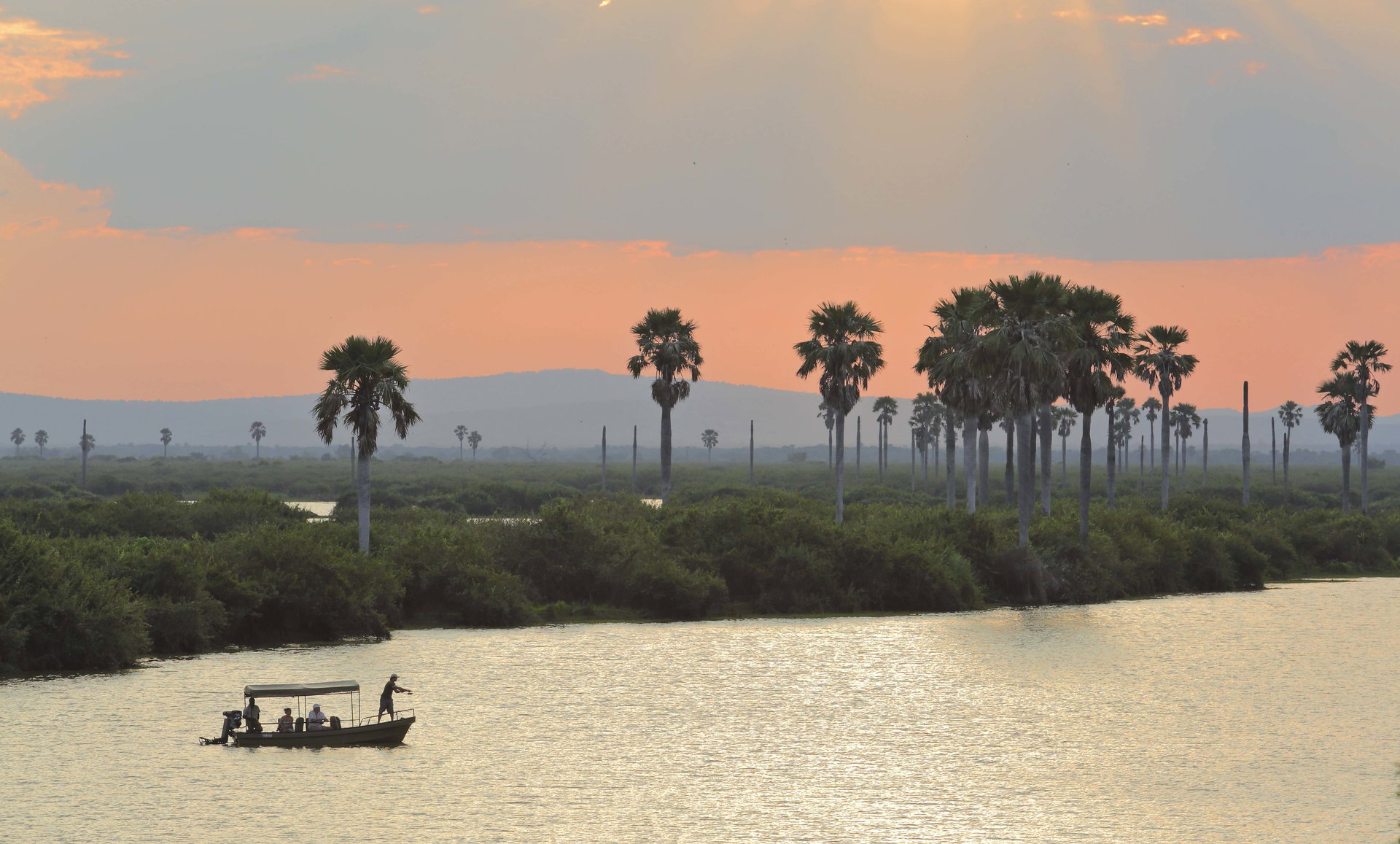 A boat on the lake among the palms at Roho ya Selous in the evening light