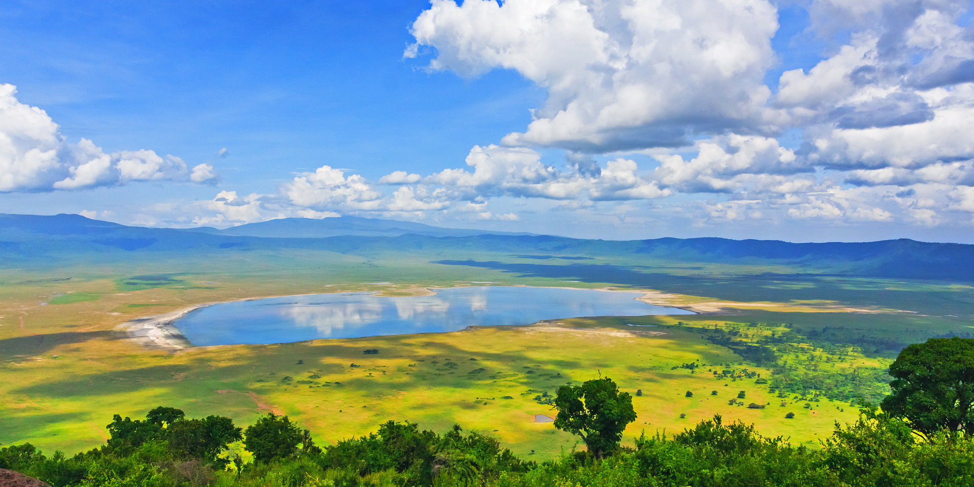 View across the green crater floor to a lake, with the crater walls behind.